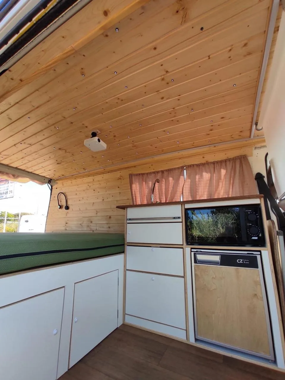 Wide interior view with light wood ceiling and kitchen on the right