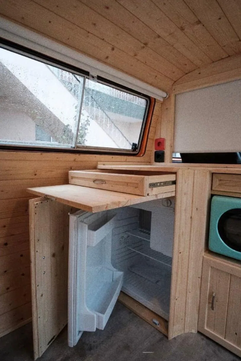 Detail of the fridge integrated into the wooden cabinets