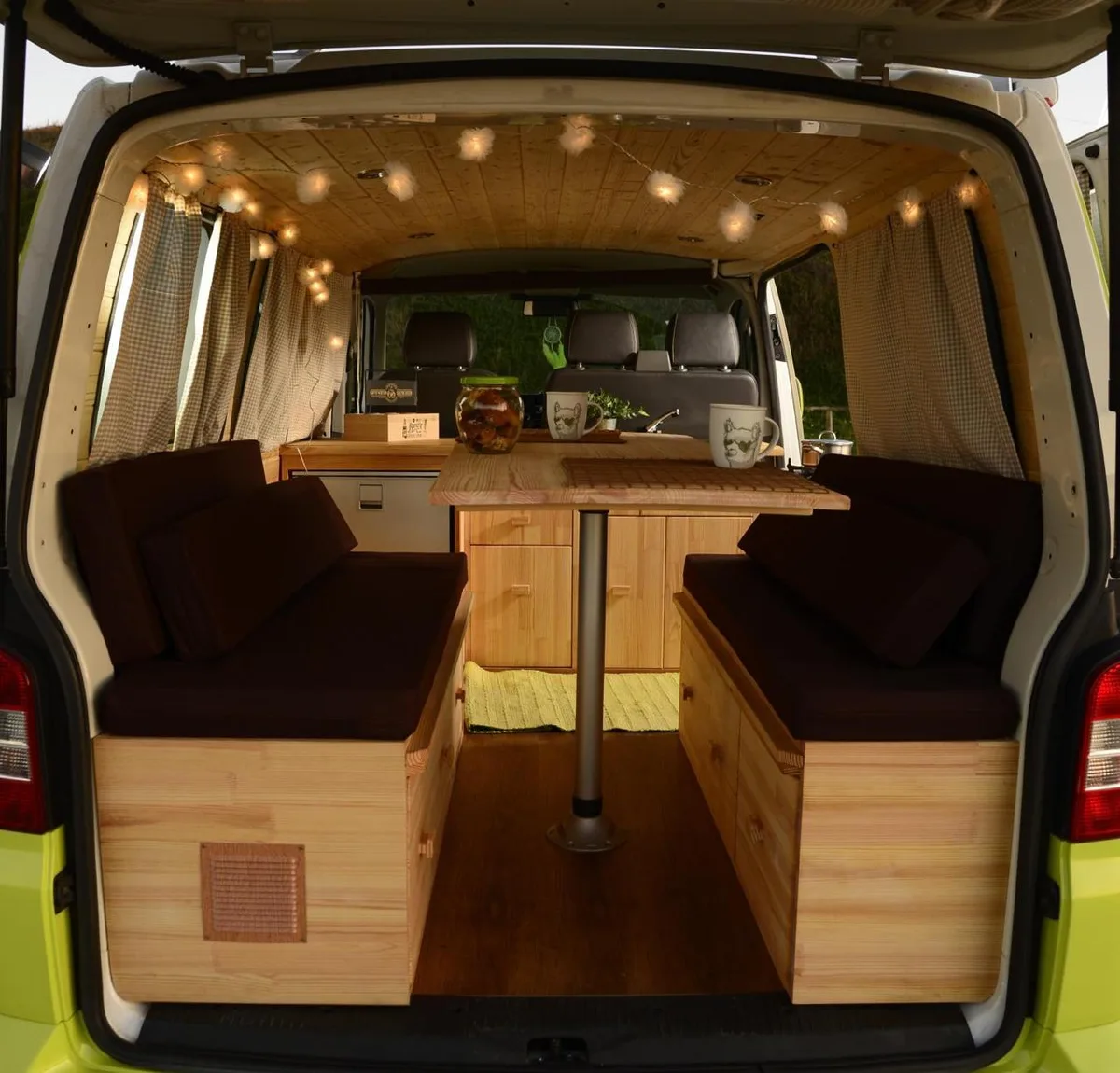Rear interior — wooden benches, folding table, fairy lights