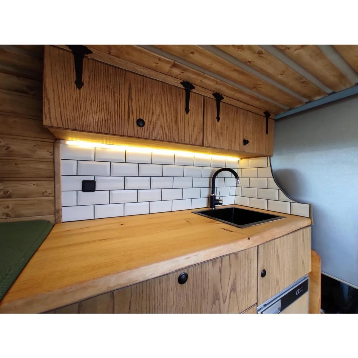 Oak kitchen with LED strip, black sink and subway tiles