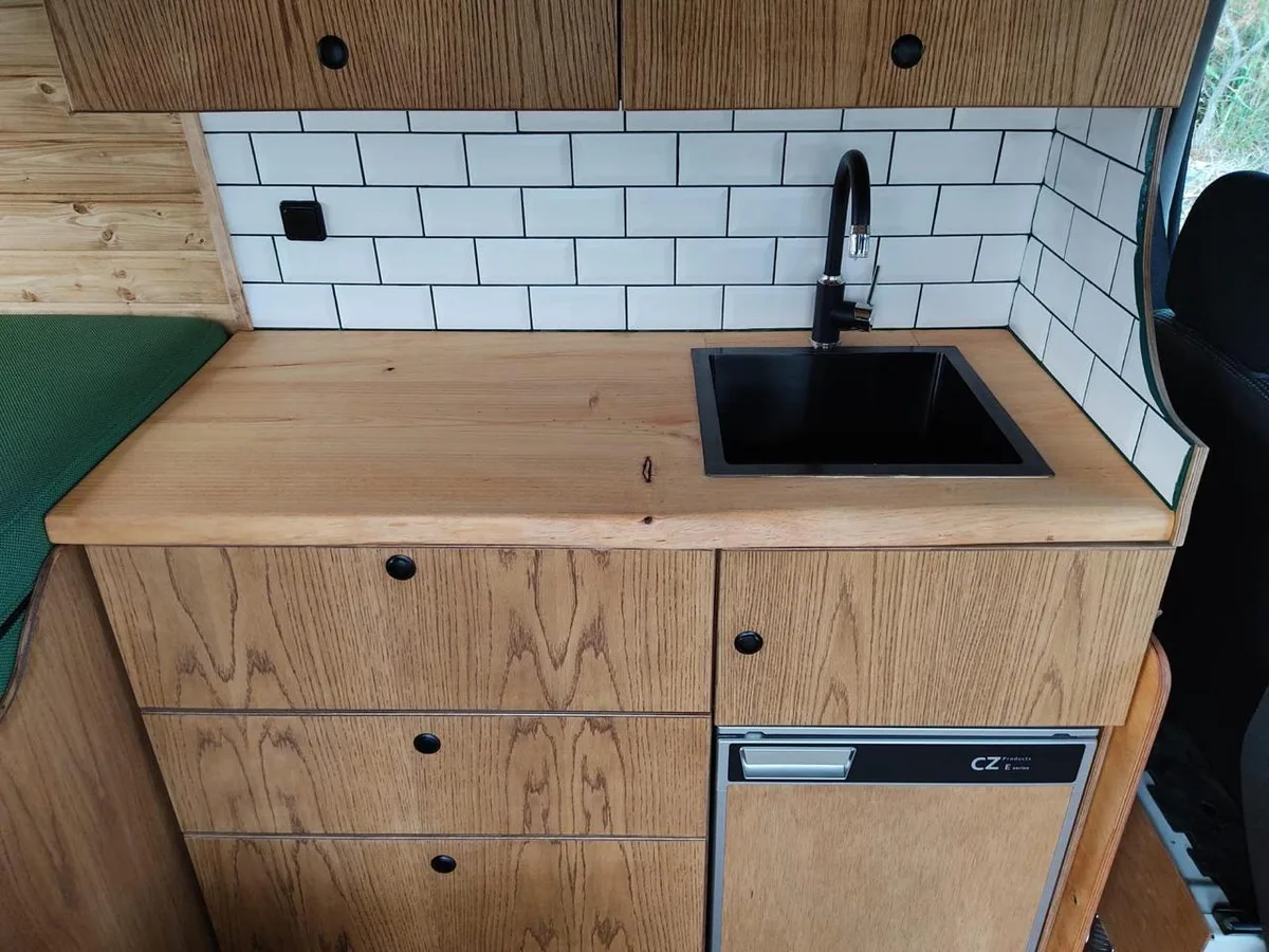 Oak counter detail with black sink and subway tiles
