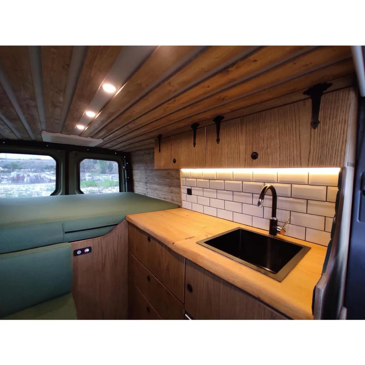 Wide-angle interior view — bed, kitchen and pine ceiling